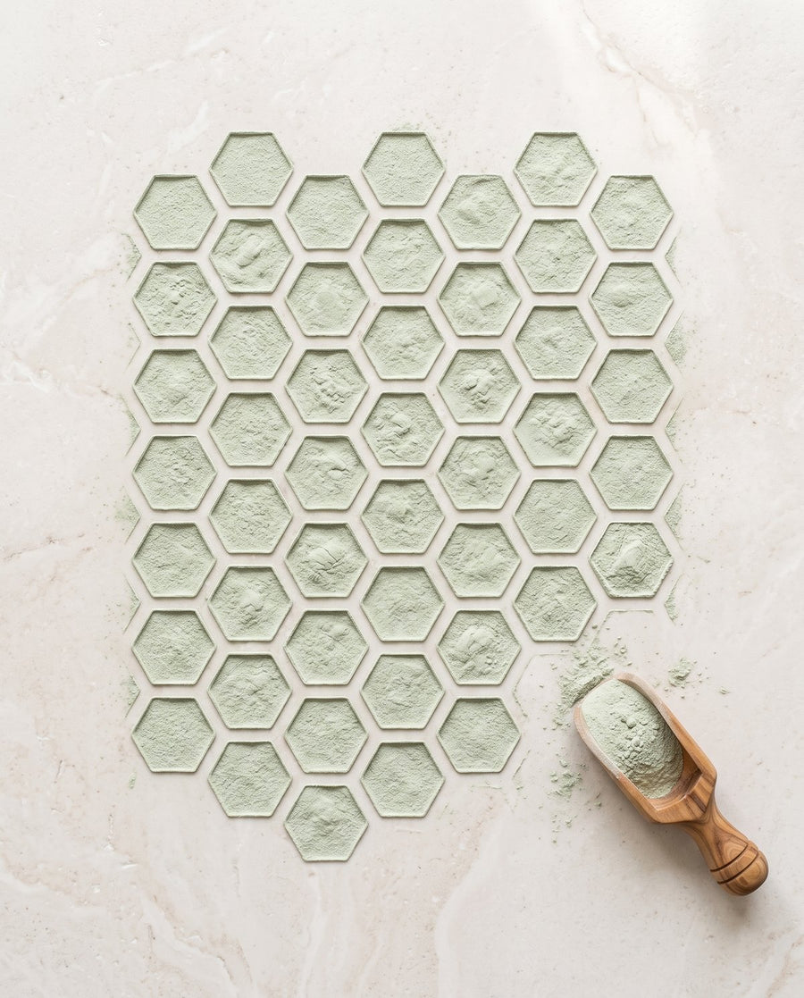 Soft green natural zeolite powder sifted into a honeycomb pattern, with a wooden scoop