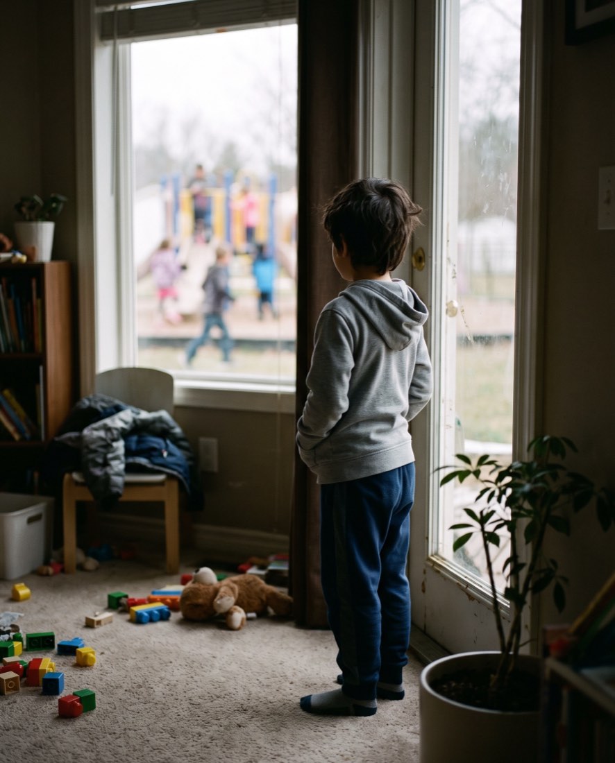 A child watching other children play from inside the house