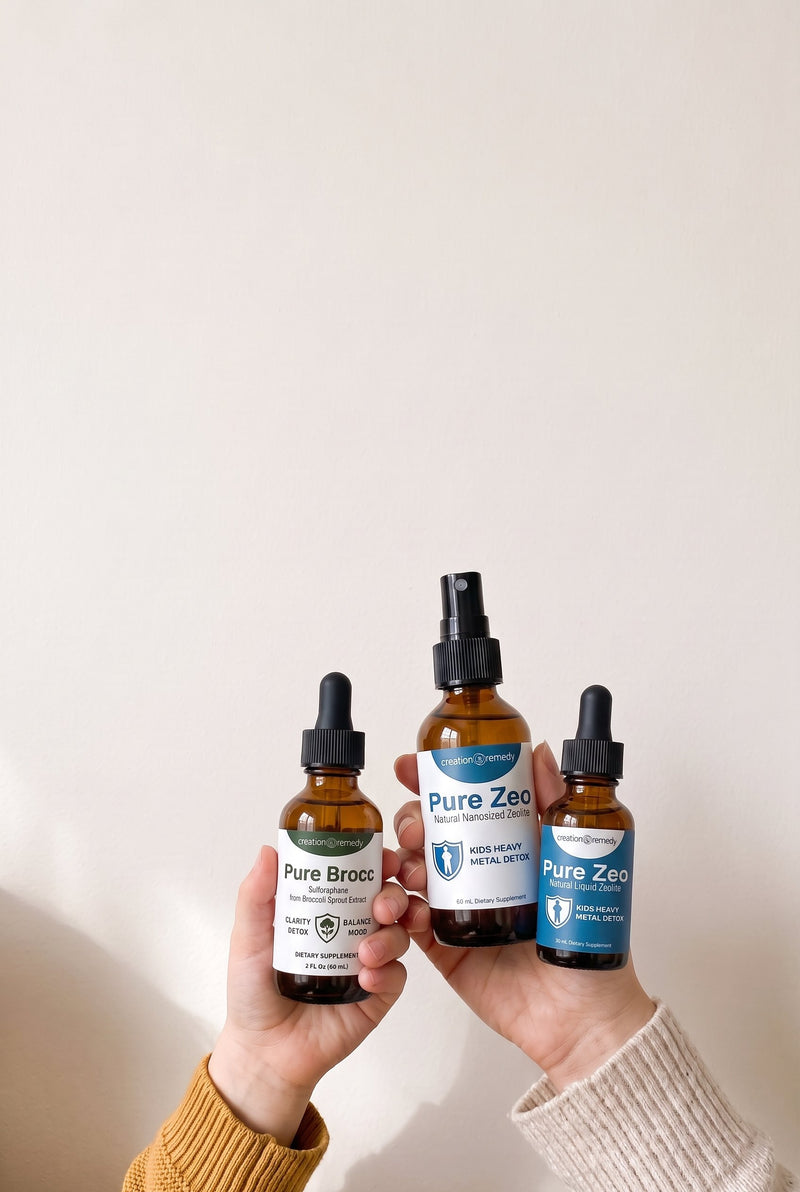 A mom&rsquo;s hand holding up the Pure Zeo spray and drops and a child&rsquo;s hand holding up Pure Brocc
